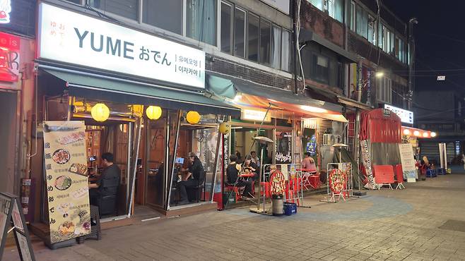 Bars just outside Seoul Central Market remain brightly lit at night. [WOO JI-WON]