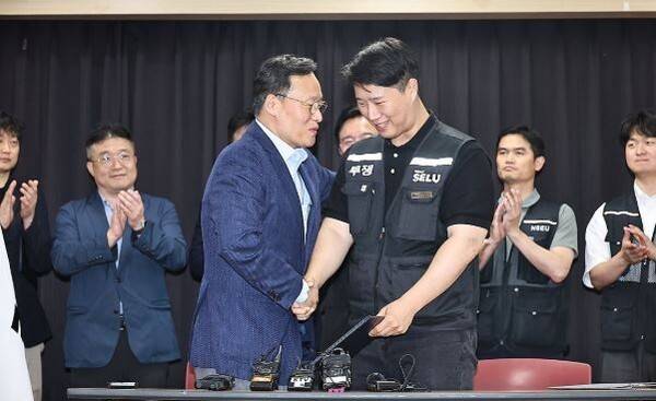20일 경기도 수원시 장안구 경기고용노동청에서 열린 삼성전자 임금협상을 마친 후 여명구 삼성전자 DS(디바이스솔루션·반도체 사업 담당) 피플팀장과 최승호 삼성그룹 초기업노동조합 삼성전자지부 위원장이 잠정 합의안에 서명한 후 손을 맞잡고 있다. [출처=연합]