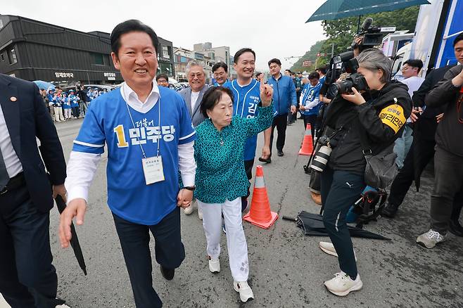 더불어민주당 정청래 총괄상임선거대책위원장이 21일 충남 공주산성시장에서 민주당 박수현 충남도지사 후보와 김영빈 충남 공주부여청양 국회의원 보궐선거 후보 지원 유세를 하는 가운데 배우 전원주 씨 손을 잡고 이동하고 있다. /연합뉴스