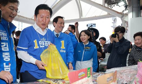 더불어민주당 정청래 총괄상임선거대책위원장이 22일 민주당 우상호 강원도지사 후보·김중남 강릉시장 후보와 강원 강릉시 주문진시장을 방문해 오징어를 구입하고 있다. [사진=연합뉴스]