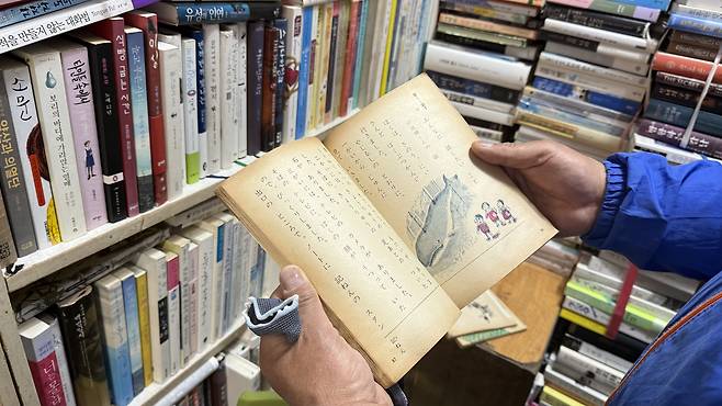 The owner of Hyorim Bookstore shows a textbook from 1960s. [WOO JI-WON]