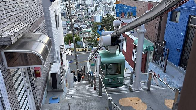 A monorail glides down the "Wish Stairs" in Dakbatgol Mural Village in Seo District. [WOO JI-WON]