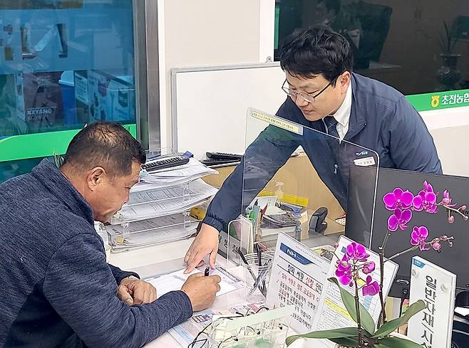 경북 성주 초전농협 자재판매장을 찾은 한 농민(왼쪽)이 직원의 설명을 들으며 하우스필름 예약 구매 신청서를 작성하고 있다. 농협경제지주