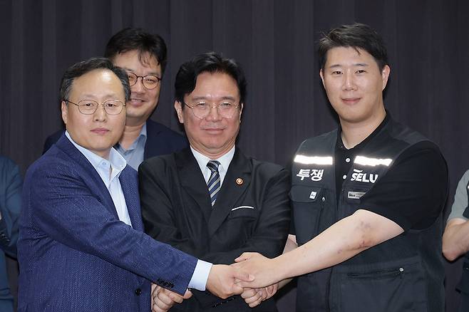 20일 경기도 수원시 장안구 경기고용노동청에서 열린 삼성전자 임금협상을 마친 후 여명구 삼성전자 DS(디바이스솔루션·반도체 사업 담당) 피플팀장과 김영훈 고용노동부 장관, 최승호 삼성그룹 초기업노동조합 삼성전자지부 위원장이 잠정 합의한에 서명한 후 손을 맞잡고 있다. 뉴시스