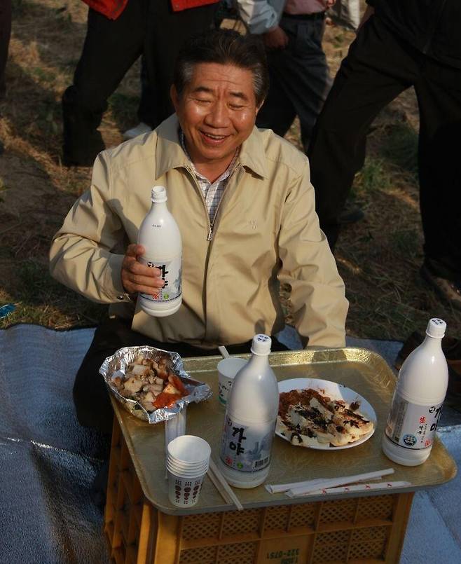 식목일 봉하마을 가꾸기 행사 후 새참시간에 막걸리 병을 들고 웃는 노무현 전 대통령. 노무현재단 제공