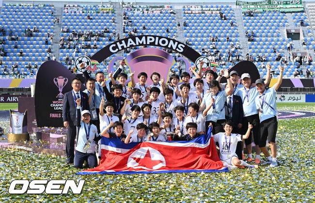 [OSEN=수원, 이대선 기자] 우승컵도, 100만 달러(약 15억 원) 우승 상금도 북한 내고향여자축구단 차지가 됐다. 논란 속 한국에서 열린 결승전에서 내고향은 일본 도쿄 베르디 벨레자를 꺾고 아시아 정상에 올랐다. 경기장 분위기 역시 마지막까지 씁쓸함을 남겼다.내고향은 23일 오후 수원종합운동장에서 열린 2025-2026 아시아축구연맹(AFC) 여자 챔피언스리그(AWCL) 결승전에서 도쿄 베르디를 1-0으로 꺾고 우승을 차지했다. 이날 공식 관중은 2670명이었다.경기 종료 후 내고향여자축구단 선수단이 인공기를 펼치고 기념촬영을 하고 있다. 2026.05.23 /sunday@osen.co.kr