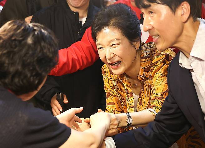 박근혜 전 대통령이 23일 오후 대구 북구 칠성시장을 찾아 추경호 국민의힘 대구시장 후보 등 일행과 함께 이동하며 상인과 인사 나누고 있다.뉴스1