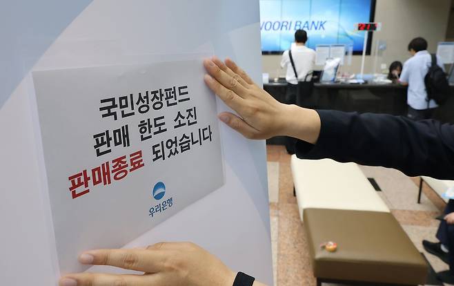 국민참여성장펀드 가입 첫날인 22일 서울 중구 우리은행 본점 영업점에서 한 직원이 한도소진으로 인한 판매종료 안내문을 붙이고 있다. 연합뉴스