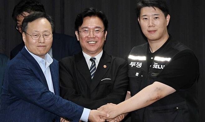 지난 20일 경기도 수원시 장안구 경기지방고용노동청에서 김영훈 고용노동부 장관(앞줄 가운데), 최승호 삼성전자 노조 공동투쟁본부 위원장(맨오른쪽), 여명구 DS(디바이스솔루션·반도체 사업 담당) 피플팀장이 손을 맞잡고 있다. 성과급 배분 방식을 두고 갈등을 빚어온 삼성전자 노사는 이날 합의를 이뤄냈다. 공동취재사진