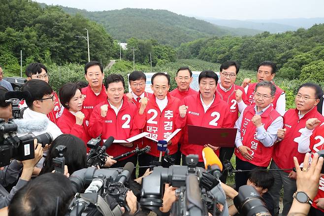추경호 국민의힘 대구시장 후보가 송언석 원내대표, 정점식 정책위의장 등 원내지도부와 28일 오전 대구 군위군 소보면 내의리 대구경북 통합신공항 예정지를 찾아 김진열 군위군수 후보자의 설명을 들은 뒤 신공항특별법 개정 당론채택 결의문을 발표하고 있다. 뉴스1