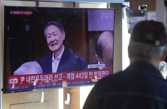 A person watches a news report of former President Yoon Suk Yeol's conviction on charges of leading an insurrection through his failed 2024 martial law bid at Seoul Station in Jung District, central Seoul, on Feb. 19. [YONHAP]