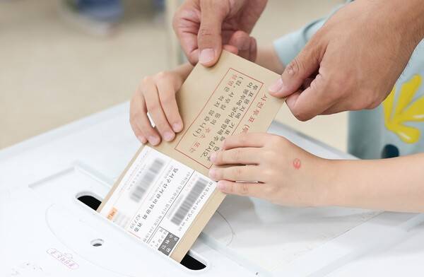제9회 전국동시지방선거 사전투표 첫날인 29일 대구 달성군선거관리위원회에 마련된 사전투표소에서 유권자가 자녀와 함께 투표하고 있다. 연합뉴스