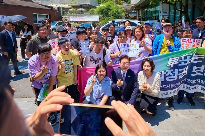 이재명 대통령과 김혜경 여사가 29일 서울 종로구 삼청동 주민센터 앞에서 발달장애인 참정권 보장 촉구 시민단체 의견을 청취한 뒤 함께 기념촬영하고 있다. 청와대 제공