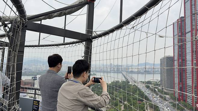 Riders on the Seouldal hot-air balloon take photos of the view. [WOO JI-WON]