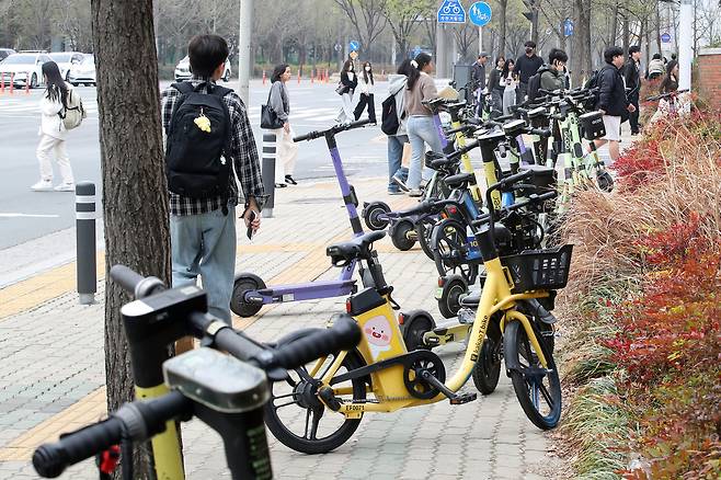 지난 3월 전동킥보드, 전기자전거 등 개인형 이동장치(PM)가 대구 달서구의 한 대학교 울타리 주변 인도에 주차돼 있다. 뉴스1