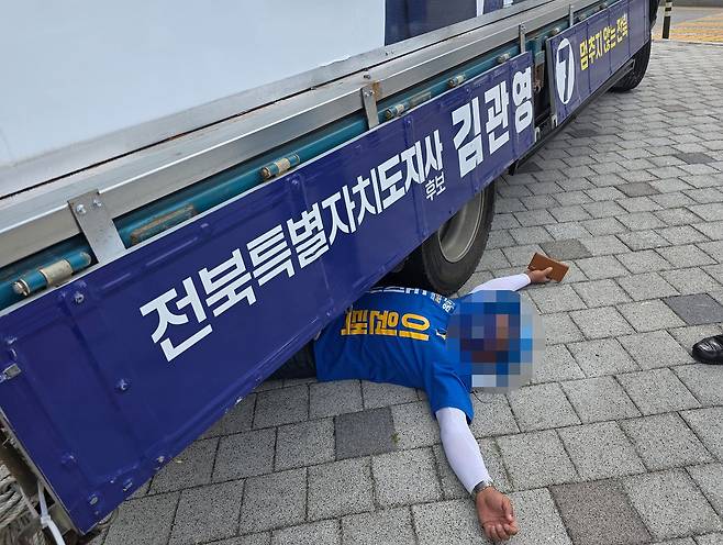 1일 전북 전주시 완산구의 한 네거리에서 이원택 더불어민주당 전북도지사 후보의 선거운동원이 김관영 무소속 후보 유세차 밑으로 들어가 드러누워 있다. 연합뉴스