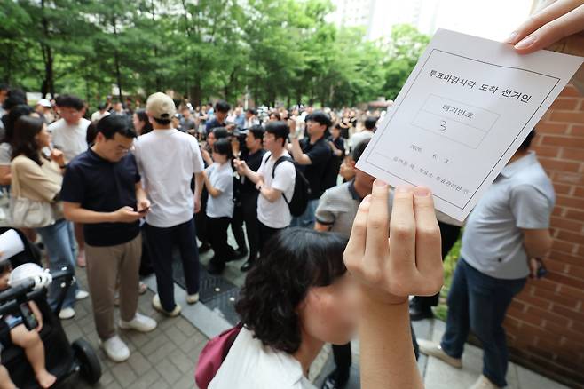 6·3 지방선거 본투표일인 3일 서울 송파구 잠실2동6투표소에서 투표용지 부족으로 유권자들이 대기하며, 현장에서 급하게 출력된 ‘투표마감시각 도착 선거인’ 임시 대기 번호표를 들고 있다./연합뉴스