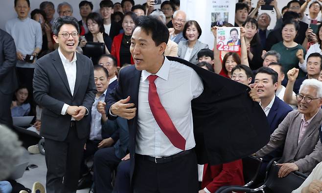 6.3지방선거에서 서울시장에 당선된 국민의힘 오세훈 후보가 4일 서울 종로구 선거사무소에서 지지자들의 환호 속에 인사를 하며 겉옷을 벗고 있다.