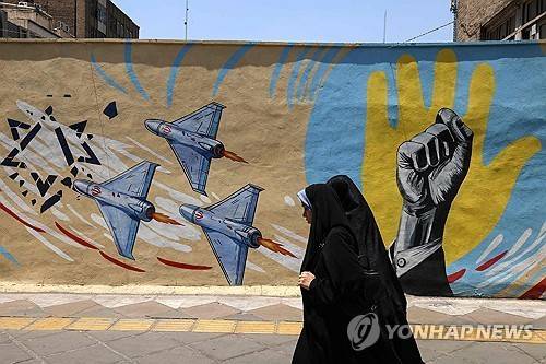 테헤란 거리의 반미 반이스라엘 벽화 앞을 지나는 여성들.(AFP/연합뉴스)