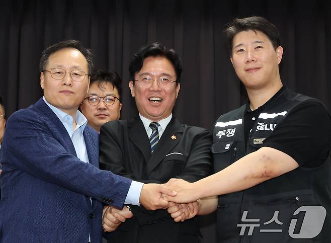 지난달 20일 경기 수원시 장안구 경기고용노동청에서 열린 삼성전자 임금협상을 마친 후 여명구 삼성전자 DS(디바이스솔루션·반도체 사업 담당) 피플팀장(왼쪽부터)과 김영훈 고용노동부 장관, 최승호 삼성그룹 초기업노동조합 삼성전자지부 위원장이 잠정 합의한에 서명한 후 손을 맞잡고 있다. 2026.5.20 ⓒ 뉴스1 김영운 기자