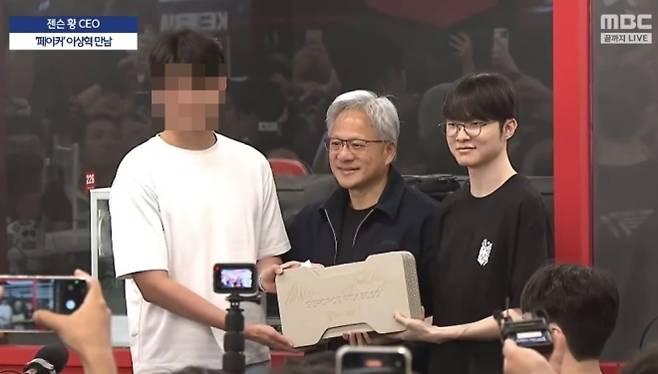 젠슨 황(가운데) 엔비디아 최고경영자(CEO)가 5일 한국을 찾아 방한 첫 일정으로 서울 마포구 티원(T1) 베이스캠프를 찾았다. 황 CEO는 e스포츠 스타 페이커(왼쪽)와 함께 엔비디아의 최신 그래픽 카드 ‘지포스 RTX 5090’에 직접 사인한 뒤 추첨을 통해 현장에 있던 한 시민에게 선물로 증정했다. 자료 : MBC