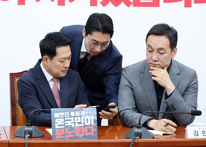 국민의힘 장동혁 대표(왼쪽)가 8일 국회에서 열린 최고위원회의에서 박준태 비서실장(가운데)이 보여주는 스마트폰 내용을 살펴보고 있다. /연합뉴스