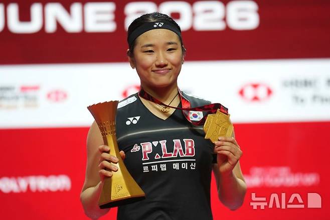 [자카르타=AP/뉴시스] 안세영(1위)이 7일(현지 시간) 인도네시아 자카르타에서 열린 '2026 세계배드민턴연맹(BWF) 월드투어 슈퍼1000 인도네시아 오픈 여자 단식 정상에 올라 트로피를 들고 시상대에서 포즈를 취하고 있다. 안세영은 결승에서 야마구치 아카네(3위·일본)를 2-0(23-21 21-12)으로 완파하고 우승하며 대회 2연패를 달성했다. 2026.06.08.