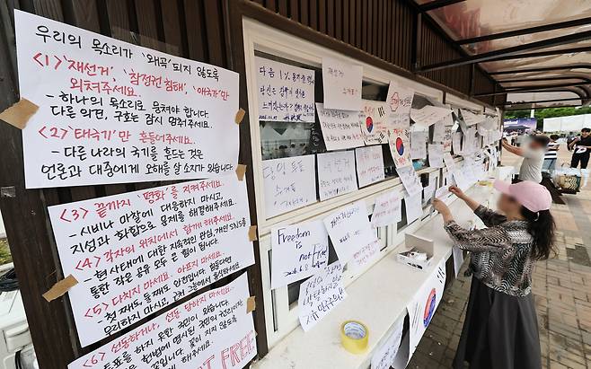 6·3 지방선거 투표지 부족 사태를 규탄하며 재선거를 요구하는 ‘잠실 개표소 봉쇄 시위’가 계속되고 있는 7일 서울 송파구 올림픽공원 핸드볼경기장 앞 매표소 부스에 재선거를 요구하는 문구 등이 적힌 종이가 붙어있다. 연합뉴스