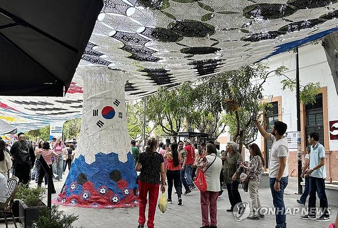 과달라하라 거리의 태극기 조형물 앞에서 사진 찍는 시민들 (사포판[멕시코 할리스코주]=연합뉴스) 오명언 기자 = 2026북중미 월드컵이 열리는 멕시코 과달라하라 인근 사포판 역사 지구에 있는 보행자 전용 거리에 이지역에서 경기를 치르는 국가를 상징하는 조형물이 설치되어 있다. 7일(현지시간) 축구유니폼을 입은 시민 등이 한국상징 조형물 아래서 기념사진을 찍고 있다. 2026.6.8 coup@yna.co.kr