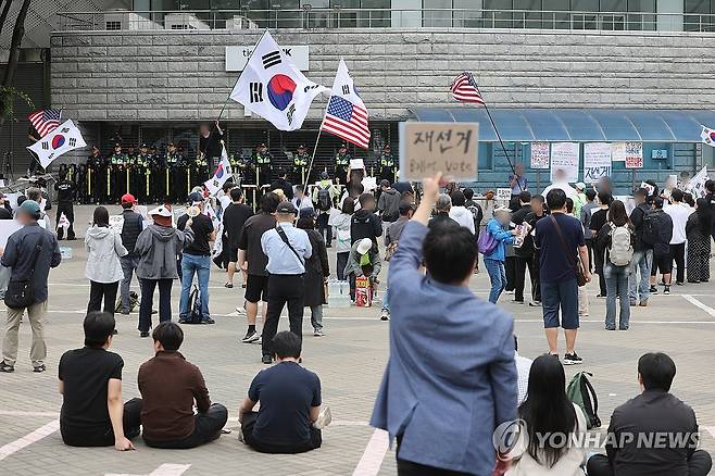 6ㆍ3 지방선거 개표소 봉쇄 시위 계속 (서울=연합뉴스) 박동주 기자 = 6·3 지방선거 투표용지 부족 사태를 규탄하며 재선거를 요구하는 '잠실 개표소 봉쇄 시위'가 계속되고 있는 8일 서울 송파구 올림픽공원 핸드볼경기장 출입구 앞에서 참가자들이 구호를 외치고 있다. 2026.6.8 pdj6635@yna.co.kr