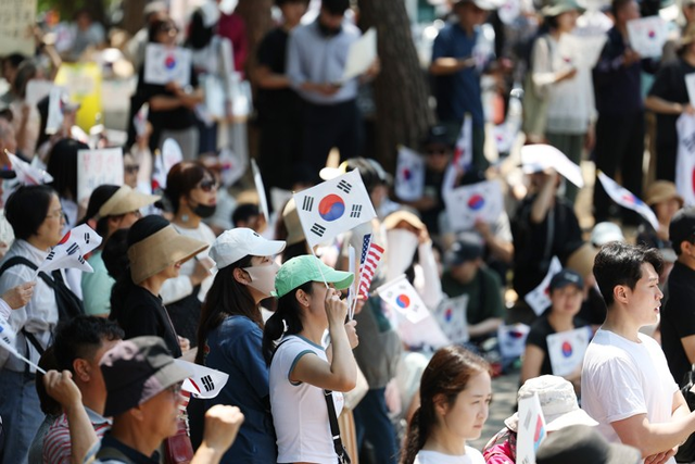 6·3 지방선거 투표용지 부족 사태를 규탄하며 재선거를 요구하는 ‘잠실 개표소 봉쇄 시위’가 계속되고 있는 9일 서울 송파구 올림픽공원 핸드볼경기장에서 한 참가자가 태극기를 흔들고 있다. [연합뉴스]