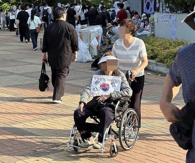 휠체어에 탄 채 시위에 참가한 노인 [촬영 전재훈]