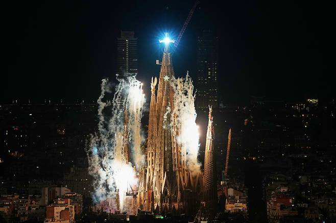 10일(현지 시각) 스페인 바르셀로나 사그라다 파밀리아 '예수 그리스도의 탑' 축복식 행사에서 정점의 십자가가 찬란한 빛을 밝히는 가운데 불꽃이 솟아오르고 있다./로이터 연합뉴스