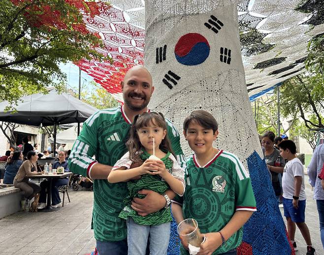 2026북중미 월드컵이 열리는 멕시코 과달라하라 인근 사포판 역사 지구에 있는 보행자 전용 거리에서 축구유니폼을 입은 시민 등이 한국상징 조형물 아래서 기념사진을 찍고 있다. 사진=연합뉴스