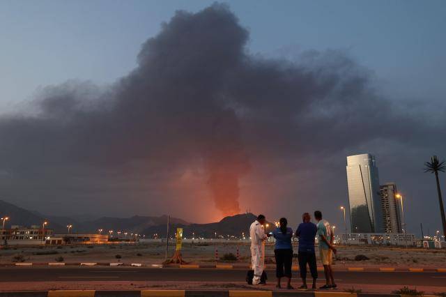 2026년 3월 3일, 이란의 공격으로 UAE 푸자이라 산업지대에서 발생한 폭발 이후 검은 연기가 치솟는 모습을 외국인 노동자들이 바라보고 있다. [사진=AFP]