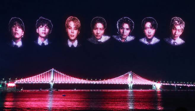 12일 밤 부산 수영구 광안리해수욕장에서 열린 BTS 부산공연 기념 특별 드론쇼에서 BTS멤버 7명의 얼굴이 밤하늘을 수놓고 있다. 사진은 광안대교의 경관조명에 이날 선보인 멤버 7명의 얼굴을 합성해 만들었다. 연합뉴스