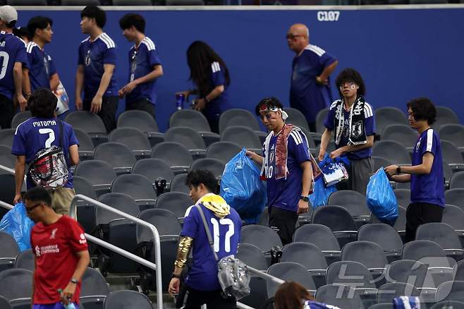 관중석을 청소하는 일본 팬들 ⓒ AFP=뉴스1