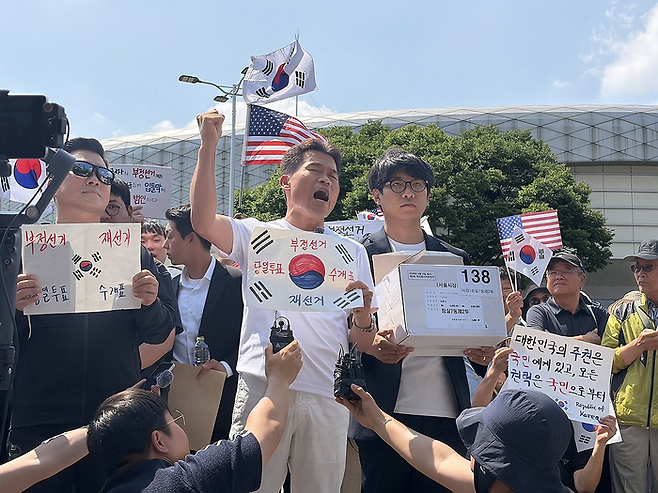 전 한국사 강사 전한길씨와 전씨의 지지자들이 지난 12일 개표소 봉쇄 시위 현장인 서울 송파구 SK핸드볼경기장 앞에서 잠실7동 제2투표소에 보관돼 있다 사라진 투표용지 보관상자 중 1개를 제보를 통해 확보했다고 주장하며 상자를 공개하고 있는 모습. [연합뉴스]