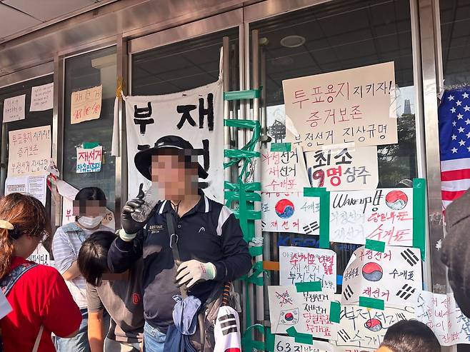 16일 오후 ‘개표소 봉쇄’ 시위가 벌어지는 서울 송파구 올림픽공원 핸드볼경기장에서 시위 참가자가 체육단체의 진입을 방해하기 위해 문을 막고 있다. 곽주영 기자