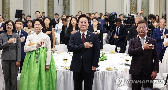 이재명 대통령 부부, 동포 오찬 간담회 참석 (로마=연합뉴스) 한상균 기자 = 이재명 대통령과 김혜경 여사가 15일(현지시간) 로마 한 호텔에서 열린 동포 오찬 간담회에서 국기에 경례하고 있다. 2026.6.15 xyz@yna.co.kr