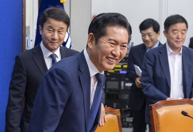 정청래 더불어민주당 대표가 17일 국회에서 열린 최고위원회의에 입장해 물건을 책상에 떨어뜨린 한정애 정책위의장을 미소 지으며 바라보고 있다. [연합뉴스]