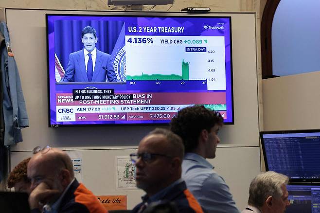 17일(현지시간) 미국 뉴욕증권거래소(NYSE)에서 트레이더들이 업무를 보는 가운데, 케빈 워시 미국 연방준비제도(Fed) 의장의 기자회견이 TV 화면에 나오고 있다. 워시 의장이 올해 네 번째로 기준금리를 동결한 결정에 대해 설명하고 있다. (사진=AFP)