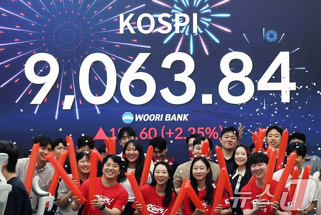 코스피 지수가 전인미답의 9000선 고지를 돌파한 18일 오후 서울 중구 우리은행 본점 딜링룸에서 직원들이 코스피 종가를 배경으로 축하 세리머니를 하고 있다.  2026.6.18 ⓒ 뉴스1 오대일 기자