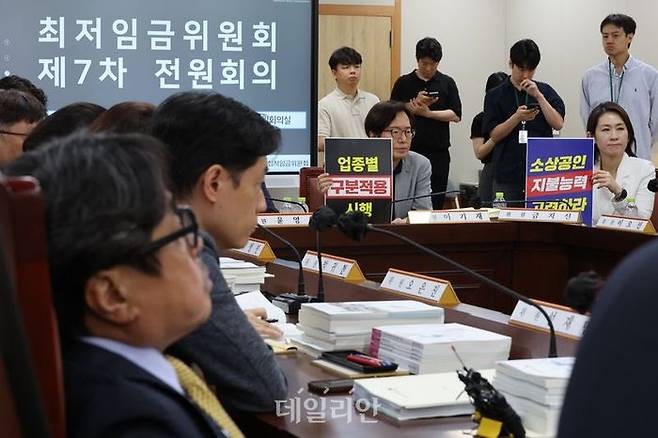 18일 정부세종청사 최저임금위원회에서 열린 제7차 전원회의에서 사용자 위원들이 최저임금의 업종별 구분적용을 요구하는 피켓을 들고 있다. ⓒ연합뉴스