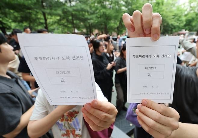 6·3 지방선거 본투표일인 3일 서울 송파구 잠실2동 6투표소에서 투표용지 부족으로 대기하던 한 유권자들이 마감시간 후 대기번호표를 들어 보이고 있다. [연합뉴스]