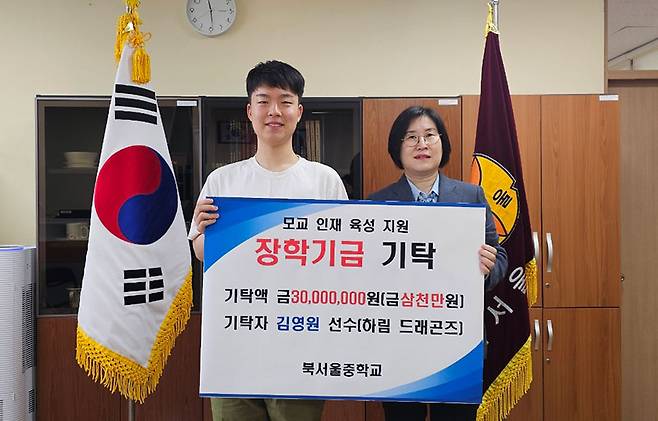 김영원(왼쪽)이 17일 모교 북서울중학교에서 기탁식을 가진 후 정영순 교장(오른쪽)과 기념 촬영 하고 있다.