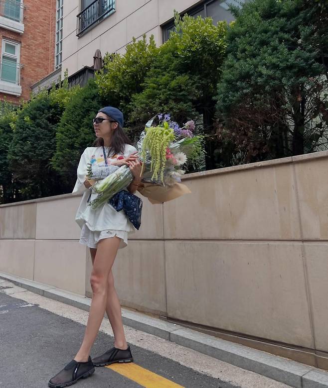 Singer Son Dam-bi shared an update on her life by posting a photo on her social media showing her smiling happily while holding a large bouquet. In the photo, Son Dam-bi drew attention by showcasing a hip fashion sense along with a slim, toned physique.On the 19th, Son Dam-bi posted several photos on her account showing her enjoying some relaxing time. She savored a happy Friday, posing on the road while holding a bouquet that appeared larger than her upper body.In particular, her lean figure stood out, complemented by a styling that matched sunglasses and a hat. Son Dam-bi also posted a photo taken from a top-down angle, jokingly asking if it was a shooting style typical of the MZ generation.Meanwhile, Son Dam-bi, born in 1983, married former speed skater Lee Kyu-hyuk in 2022 and has a daughter.