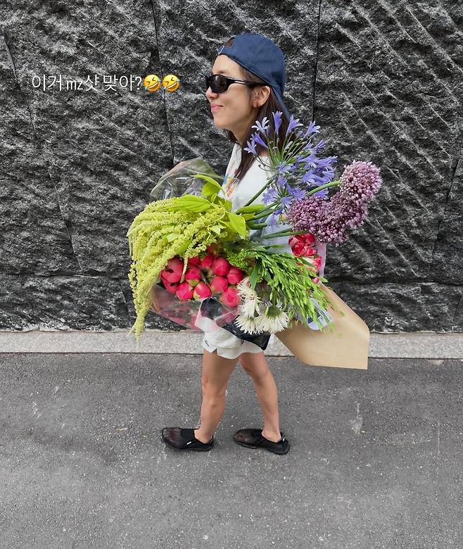 Singer Son Dam-bi shared an update on her life by posting a photo on her social media showing her smiling happily while holding a large bouquet. In the photo, Son Dam-bi drew attention by showcasing a hip fashion sense along with a slim, toned physique.On the 19th, Son Dam-bi posted several photos on her account showing her enjoying some relaxing time. She savored a happy Friday, posing on the road while holding a bouquet that appeared larger than her upper body.In particular, her lean figure stood out, complemented by a styling that matched sunglasses and a hat. Son Dam-bi also posted a photo taken from a top-down angle, jokingly asking if it was a shooting style typical of the MZ generation.Meanwhile, Son Dam-bi, born in 1983, married former speed skater Lee Kyu-hyuk in 2022 and has a daughter.