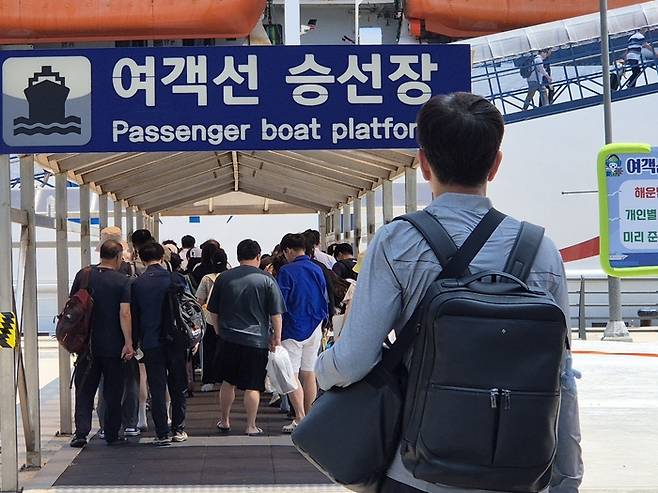 지난 17일 관광객들과 청년들이 사동항 승선장에서 육지로 나가기 위해 여객선에 오르고 있다. <홍준기 기자>