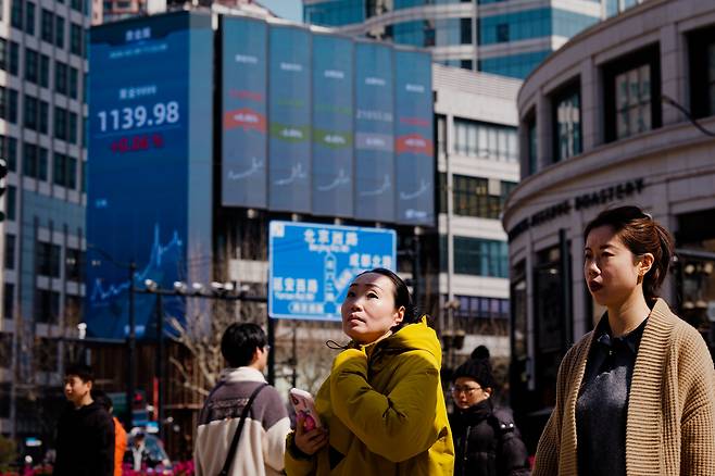 중국 상하이에서 시민들이 증시 및 경제 데이터가 표시된 대형 전광판 아래를 지나가고 있다. /EPA